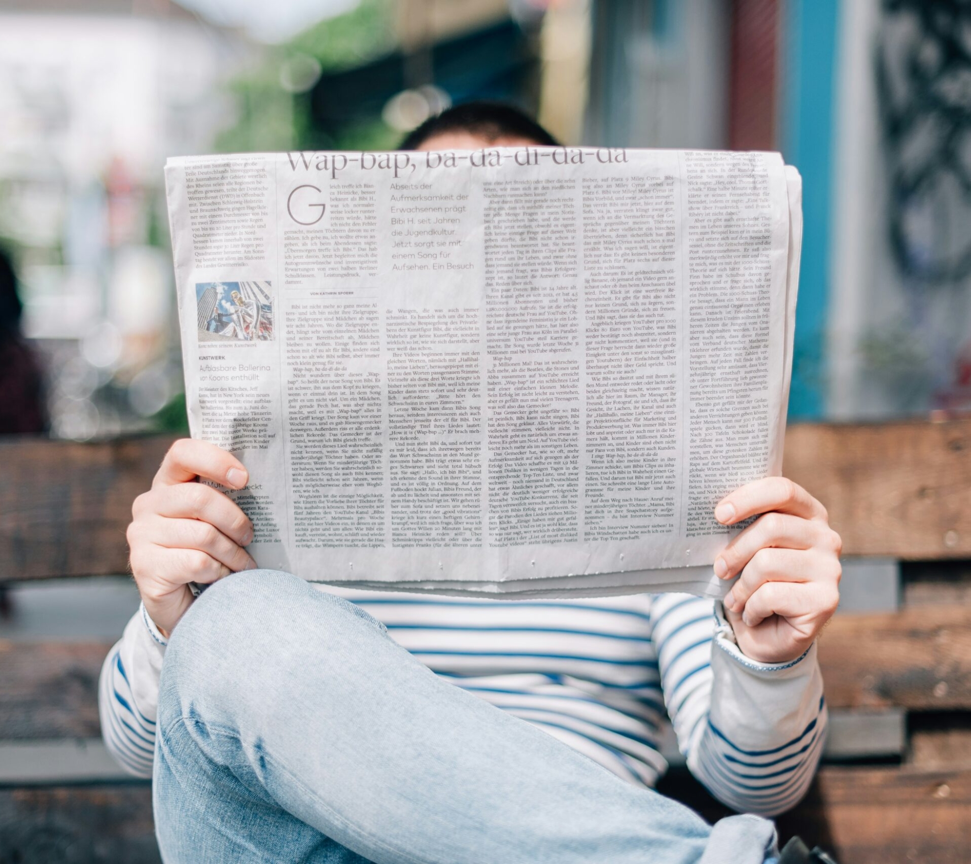 man sitting on bench reading newspaper